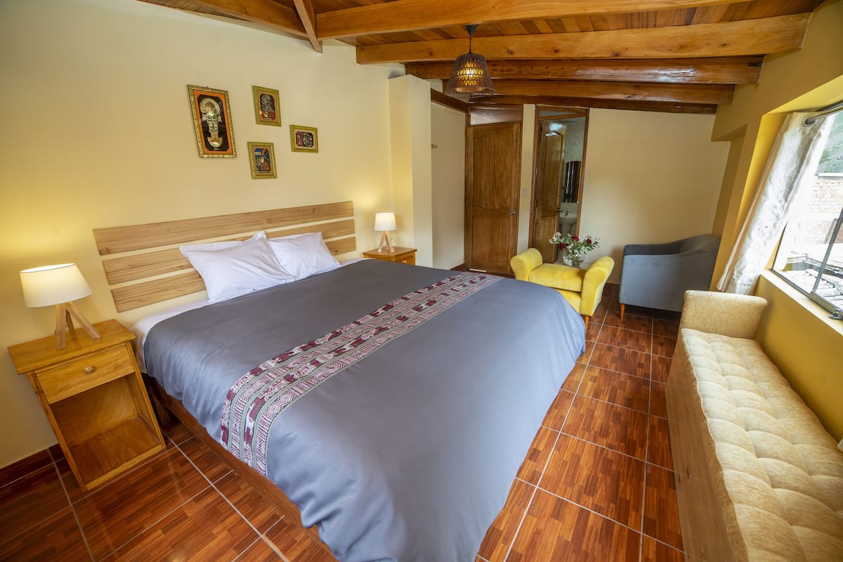 A bedroom with a bed, bedside tables, a chair, a sofa, and a window.