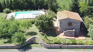 A stone house with a tiled roof, a swimming pool, and a stone bridge. - Villa San Martino (Pomarance)
