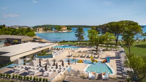 Un resort con diverse piscine, lettini e vista sul mare.