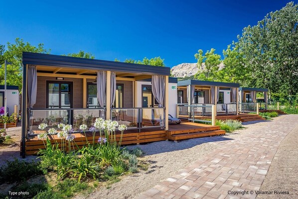 A row of modern, covered outdoor cabins with glass railings, wooden decks, and a gravel pathway leading to them. - Victoria Mobilehome Camping Padova (Rab)