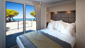 Una camera d'albergo con un letto grande, vista sulla spiaggia e una porta scorrevole in vetro.
