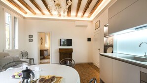 Un cuarto acogedor con una mesa de comedor lista para el desayuno, una cocina con un lavamanos moderno y vigas de madera a la vista en el techo.
