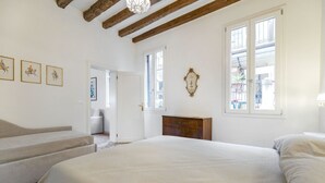 Un dormitorio con una cama grande, cabecera de madera, una escalera de madera y una puerta que da a otra habitación.