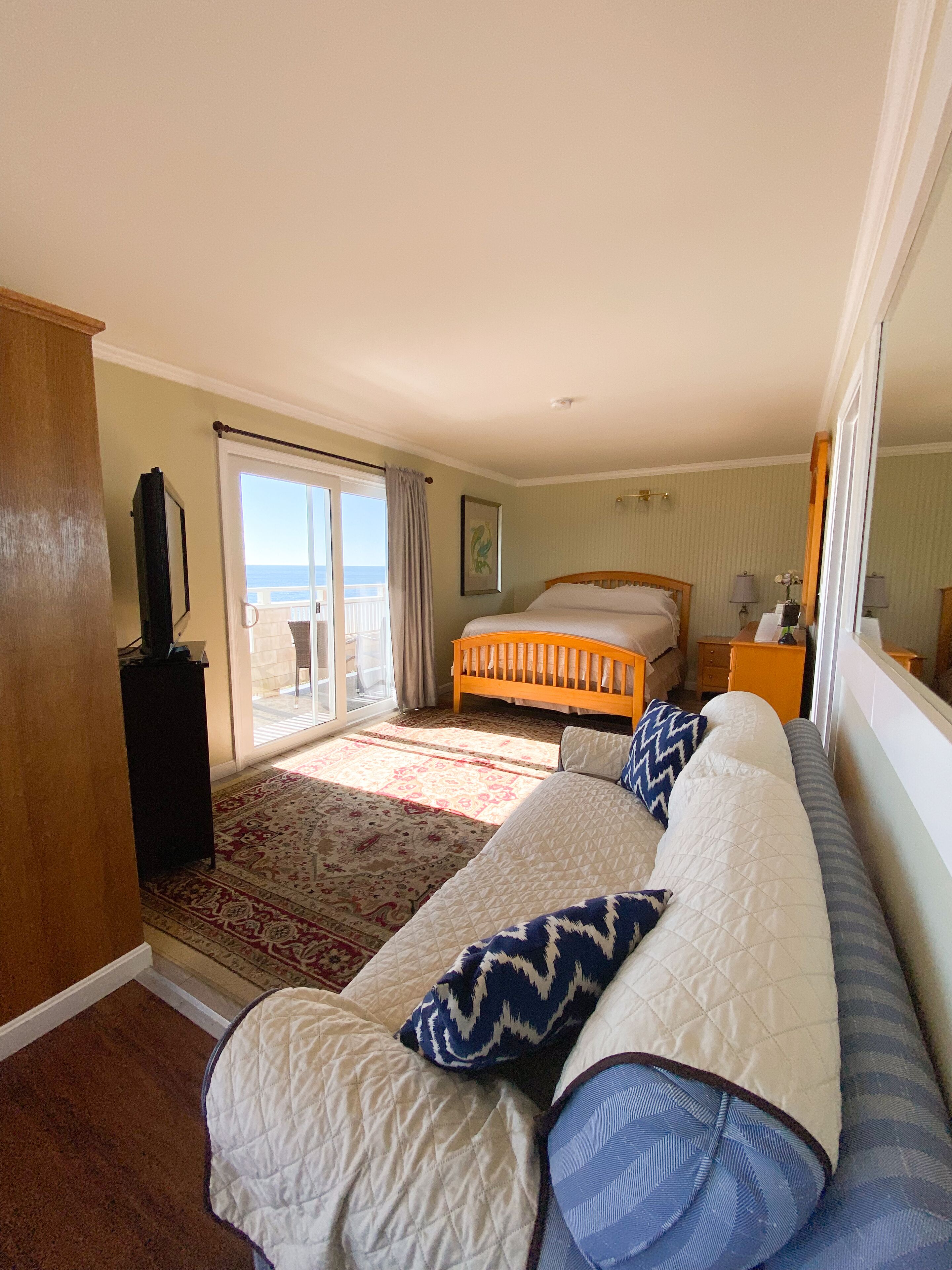 Une chambre avec un grand lit, un canapé, une télévision et une vue sur la mer.