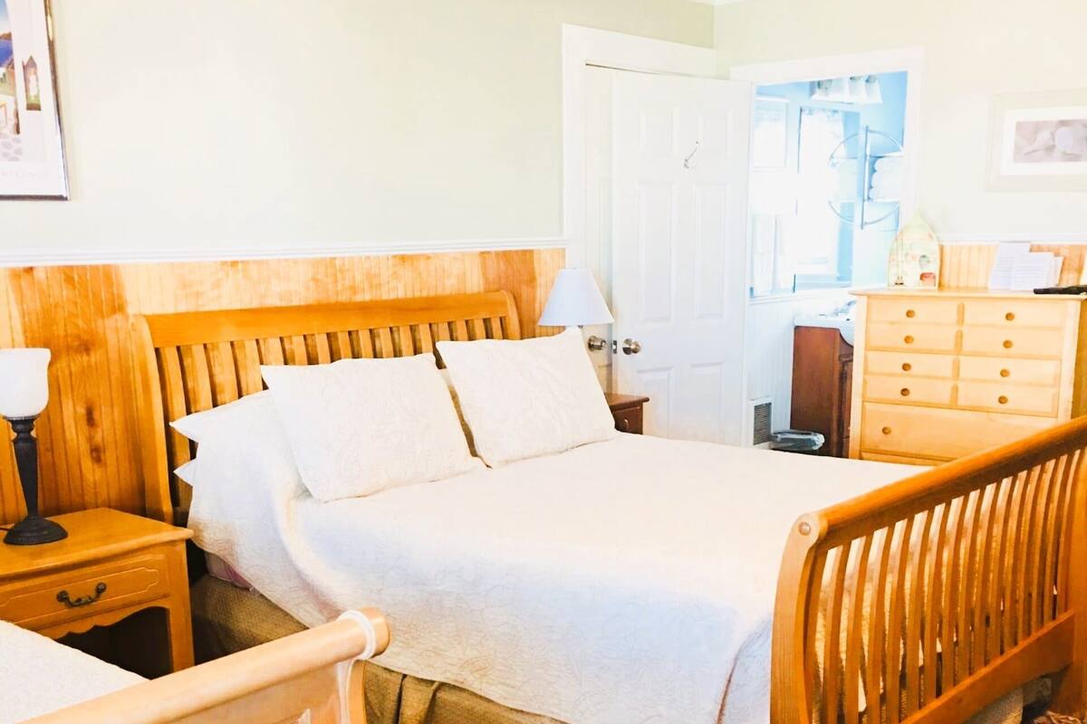 A bedroom with a wooden bed, a nightstand, a dresser, and a patterned rug.
