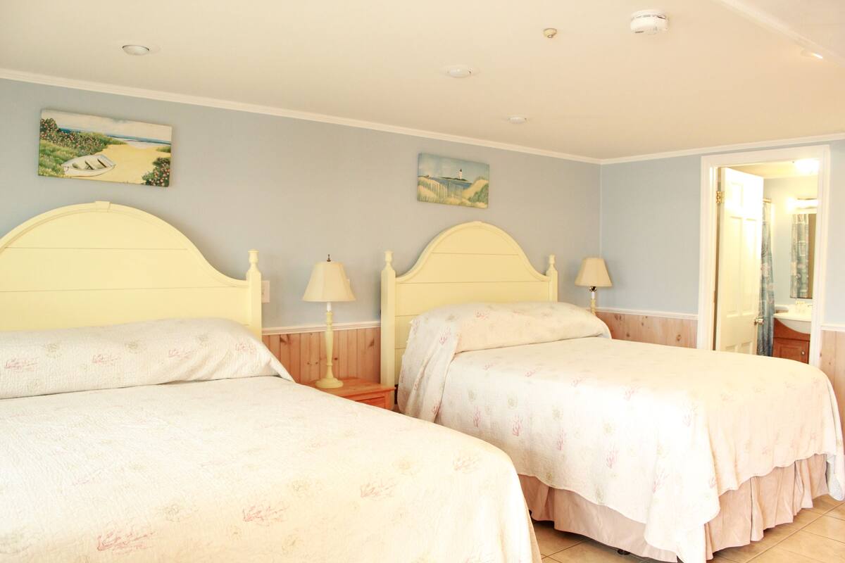 A bedroom with two beds, each with a headboard, bedside lamps, and floral bedding.