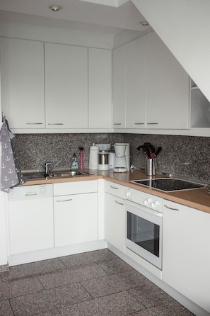 A kitchen with white cabinets, a granite countertop, a stainless steel sink, a coffee maker, and a microwave.