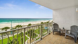 A balcony with a view of a beach, two chairs, and a small table. - The Summit 531 (Panama City Beach)