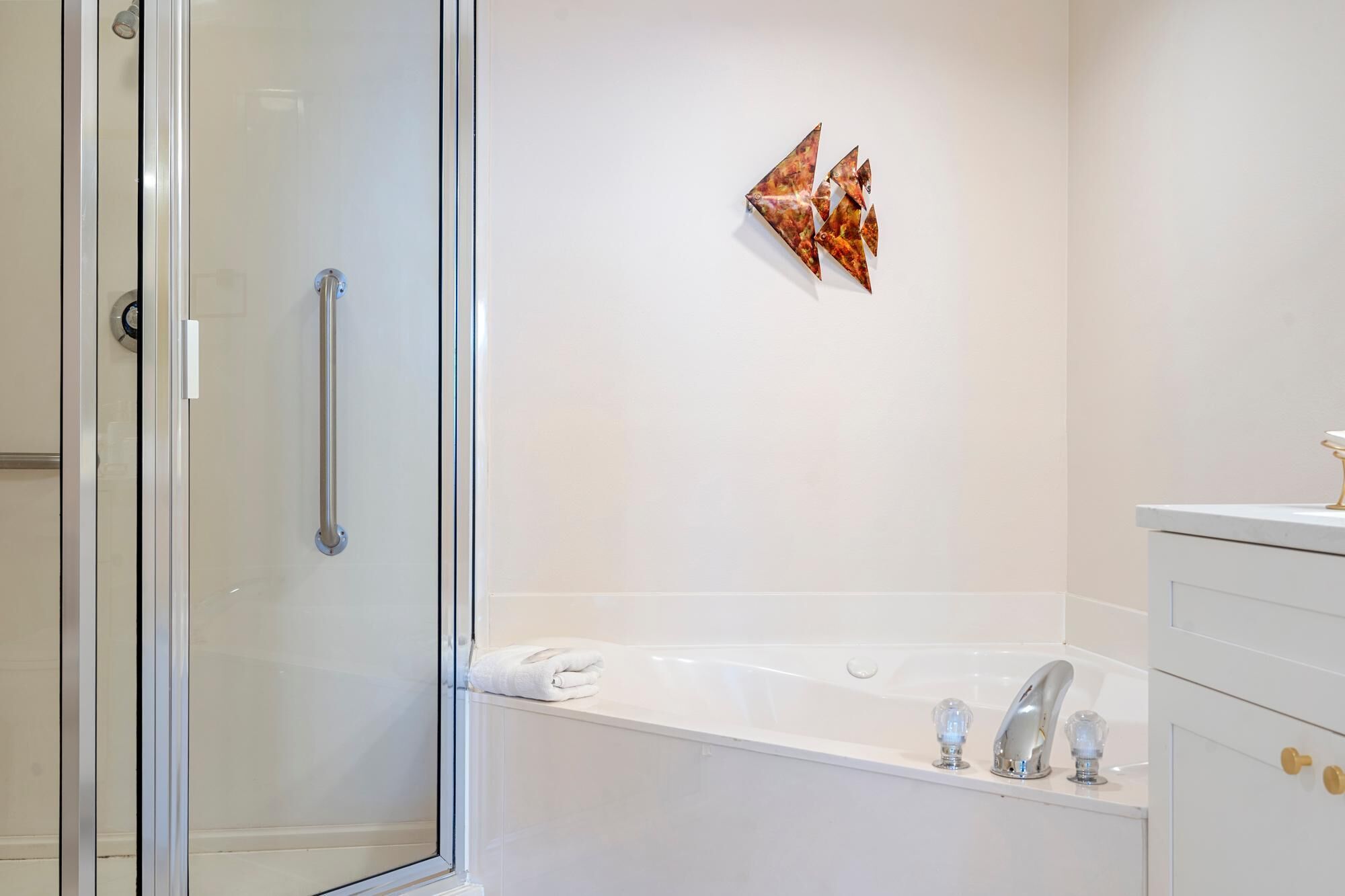 Un baño moderno con cabina de ducha de vidrio, una bañera blanca y un perchero de toallas en la pared.