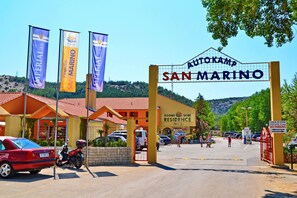 A hotel entrance with a sign reading "Autokamp San Marino" and flags for "Imperial" and "Camping San Marino."