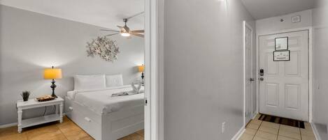Un dormitorio con cama, mesitas de noche, ventilador de techo e iluminación empotrada en la pared.