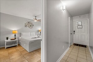 A bedroom with a bed, bedside tables, a ceiling fan, and a wall-mounted light fixture.