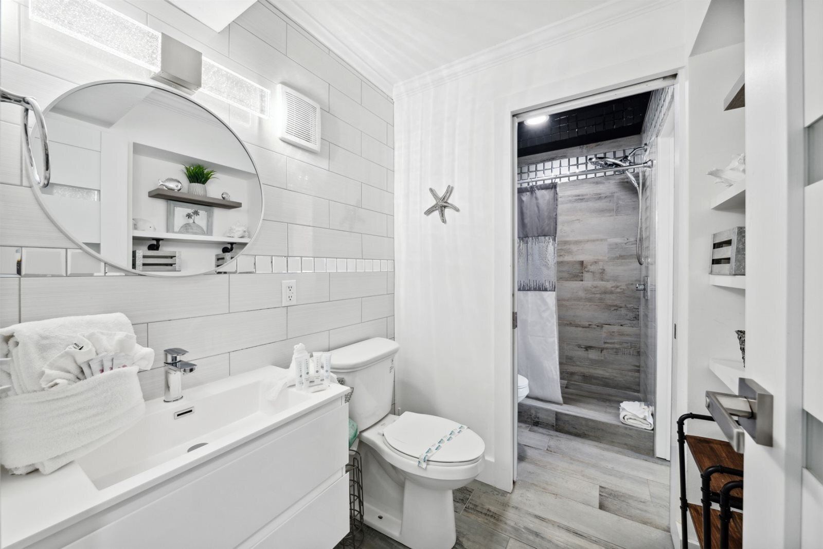 Ein modernes Badezimmer mit Waschbecken, Toilette und Duschbereich, alles in Weiß.