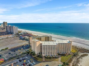 A beachfront hotel with multiple floors, a parking lot, and a view of the ocean. - Top Of The Gulf 815 (Panama City Beach)