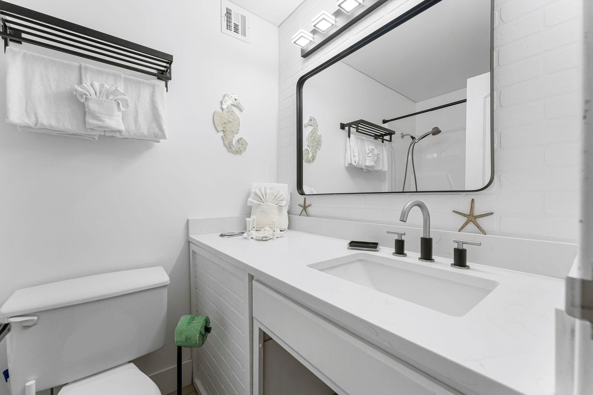 A modern bathroom with a white sink, mirror, and towel rack.