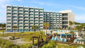 A multi-story hotel with a modern design, featuring balconies and a pool area with lounge chairs. - Top Of The Gulf 815 (Panama City Beach)