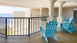 A balcony with a view of the ocean, featuring blue Adirondack chairs and a concrete floor. - Top Of The Gulf 815 (Panama City Beach)