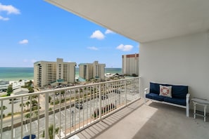 A balcony with a view of the ocean and hotel buildings.