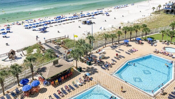 A beach resort with multiple swimming pools, sun loungers, and umbrellas.