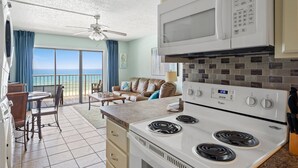 A kitchen with a stove, microwave, and a view of the ocean.