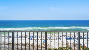 A beach with umbrellas and lounge chairs, a clear blue sky, and the ocean.