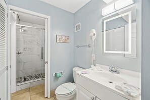 Ein Badezimmer mit Dusche, Toilette, Waschbecken und Spiegel.