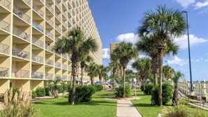 Ein Hotel mit modernem Design, das zahlreiche Balkone und einen gepflegten Außenbereich mit Palmen und einem Weg bietet.