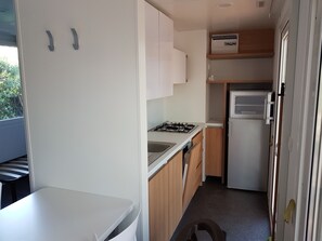 A compact kitchen with white cabinets, a gas stove, a sink, and a refrigerator. - Victoria Mobilehome Camping Imperial (Vodice)