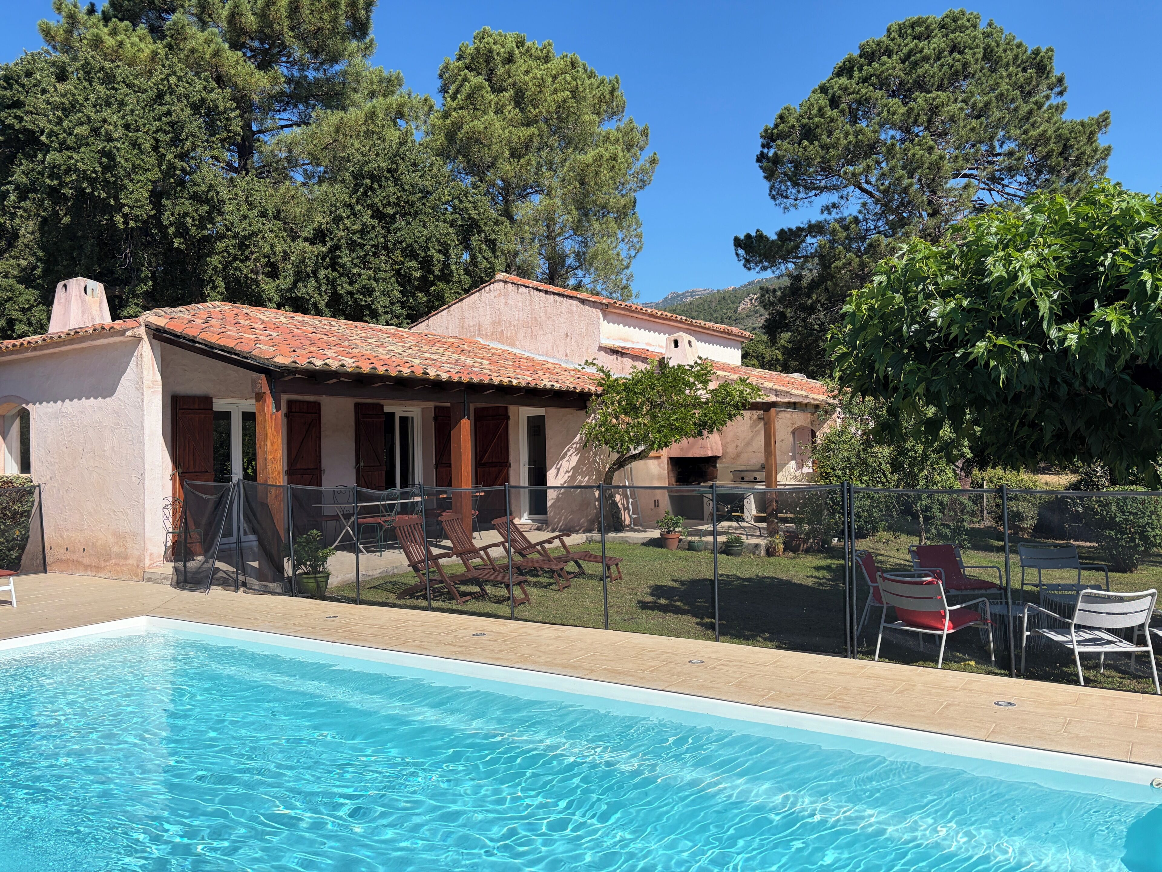 A swimming pool with lounge chairs and a building with a tiled roof.