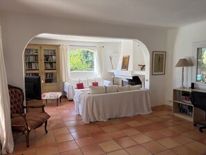Een gezellige woonkamer met een open haard, een zithoek, een televisie en een boekenkast.