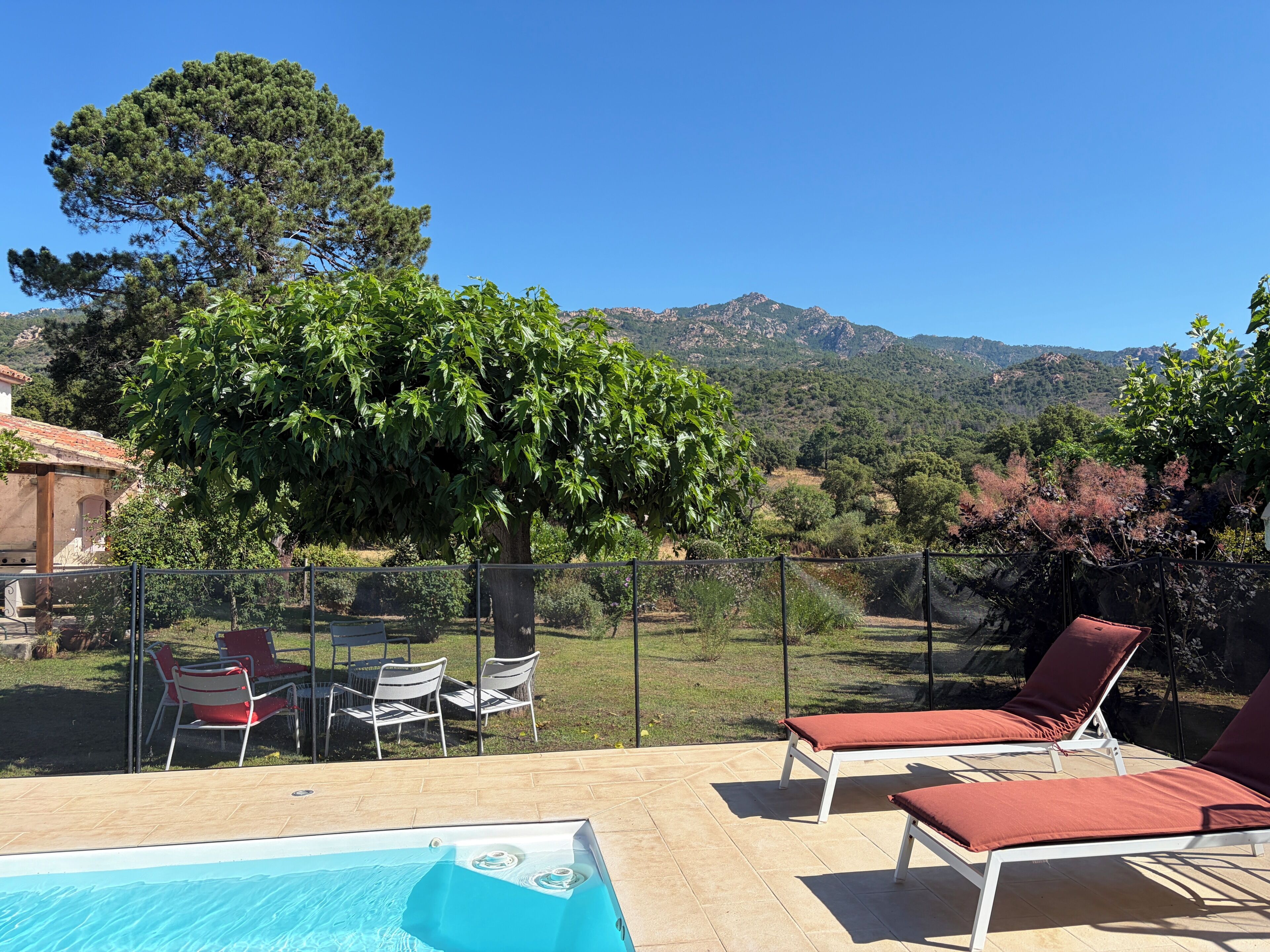Zona de piscina con sillones de descanso y vistas a un paisaje montañoso.