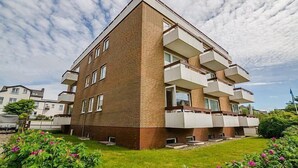 A modern apartment building with a unique architectural design, featuring multiple balconies and a brick facade. - Appartement Kiek in 09 Westerland (Westerland)