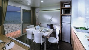A modern interior with a dining area, kitchen, and a view of the sea. - Victoria Mobilehome Camping Dole (Podgora)