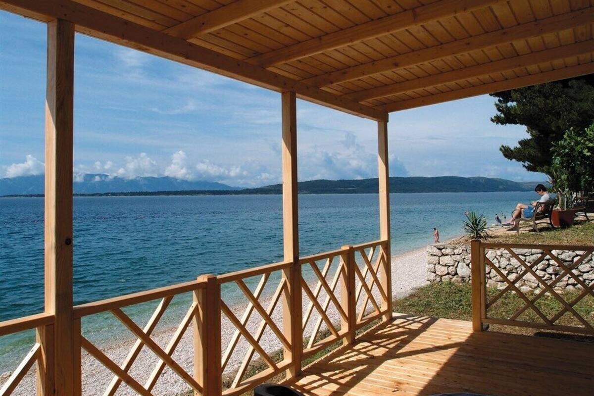 A wooden deck with a view of a lake and mountains.