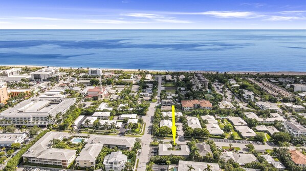 An aerial view of a coastal residential area with a mix of single-family homes and apartment buildings, a central road, and a beach in the background. - Seaside Escape/Luxury Unit /Walk to Beach (Delray Beach)