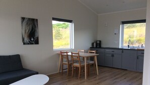 A modern kitchen with a dining area, wooden flooring, and large windows. - Hvammstangi Hill Homes (Hvammstangi)
