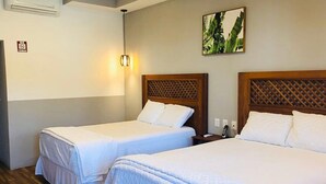 Ein Hotelzimmer mit zwei Einzelbetten, einem Holzkopfteil, einer Wandleuchte und einem kleinen Gemälde.