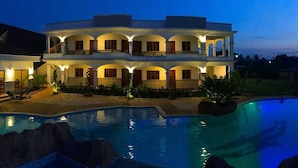 Ein mehrstöckiges Gebäude mit Pool, Außenbereich und gut beleuchteten Balkonen.