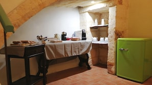Une cuisine avec une table mise pour le thé, une machine à café et un réfrigérateur vert.