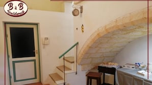 Une pièce avec un escalier, une table sur laquelle se trouve une boîte à thé et une horloge murale.