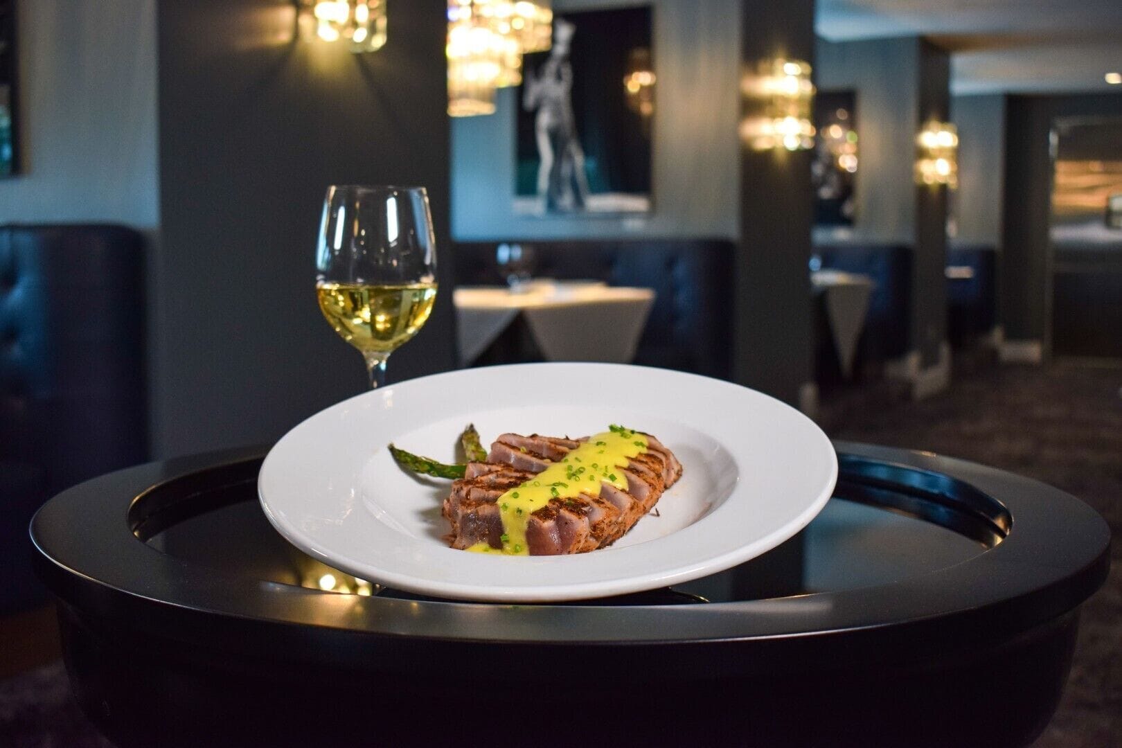 A dining table with a plate of food and a glass of wine.