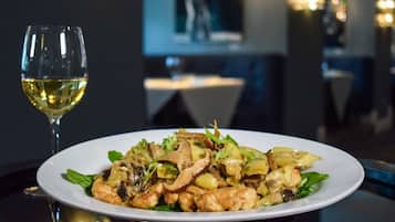 A plate of food with a glass of white wine on a table in a restaurant.