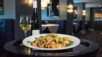 A dining table with a plate of food and two glasses of wine in a restaurant setting.