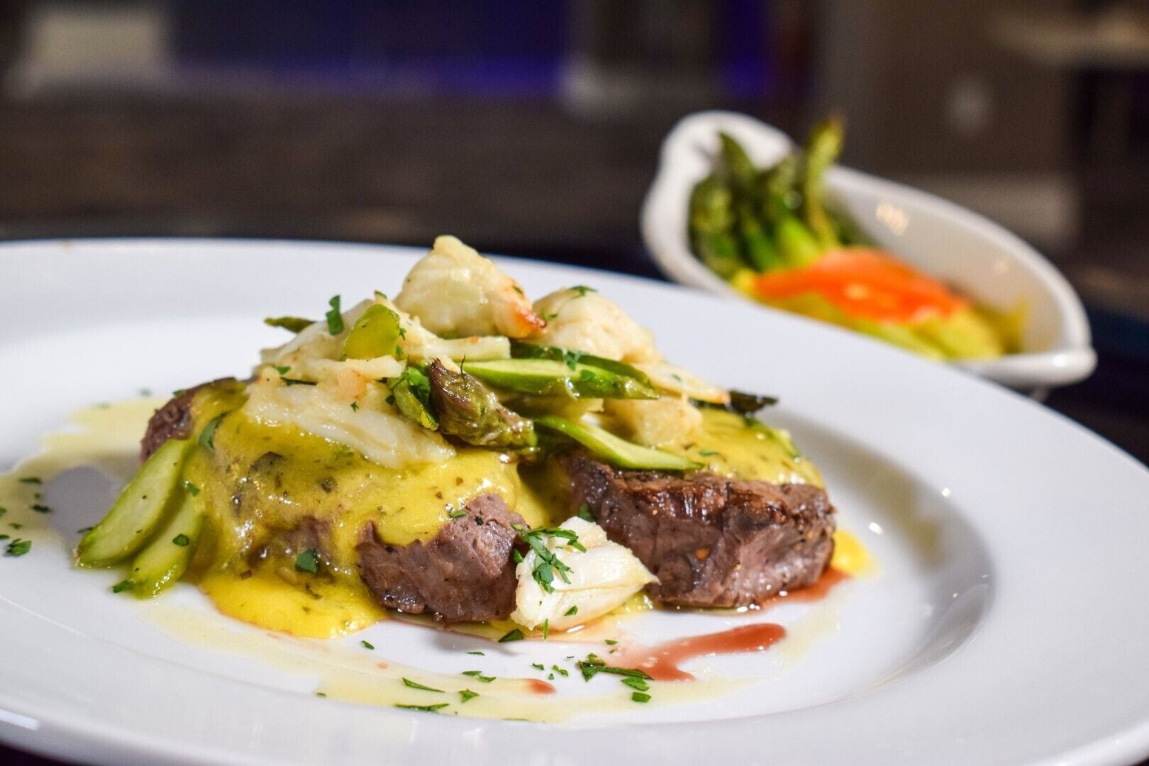 A plate of food with a steak and vegetables, possibly asparagus, on a white plate.