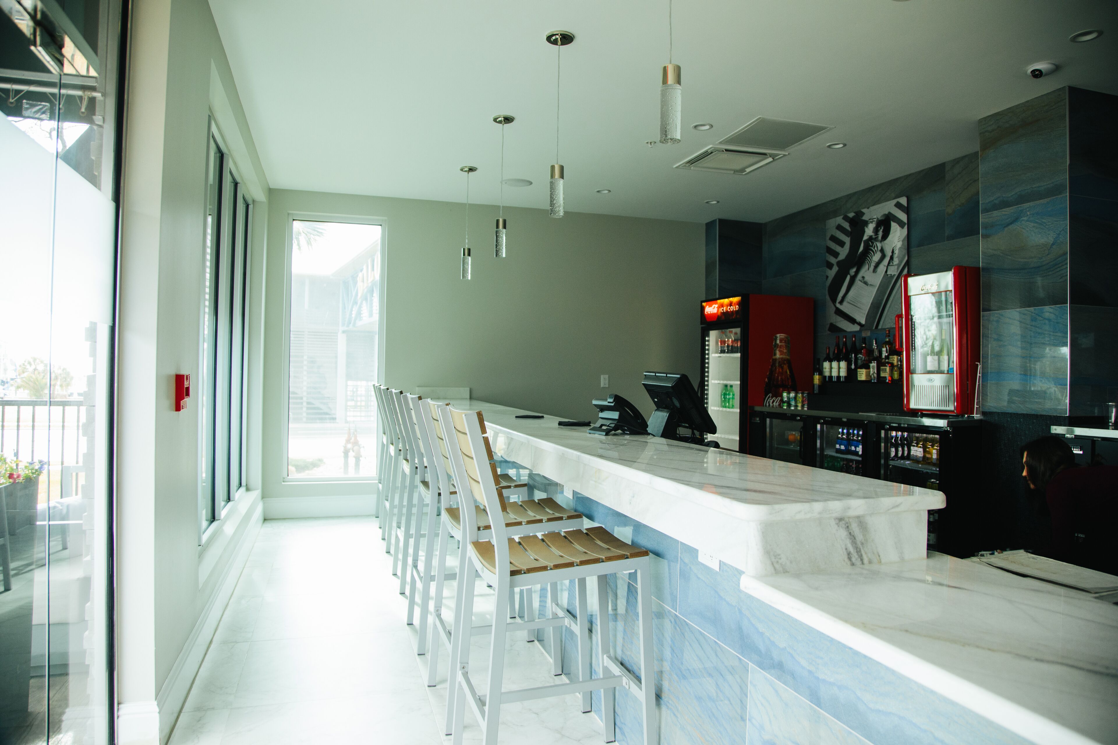 A modern bar area with a long counter, multiple bar stools, and a large mural on the wall.