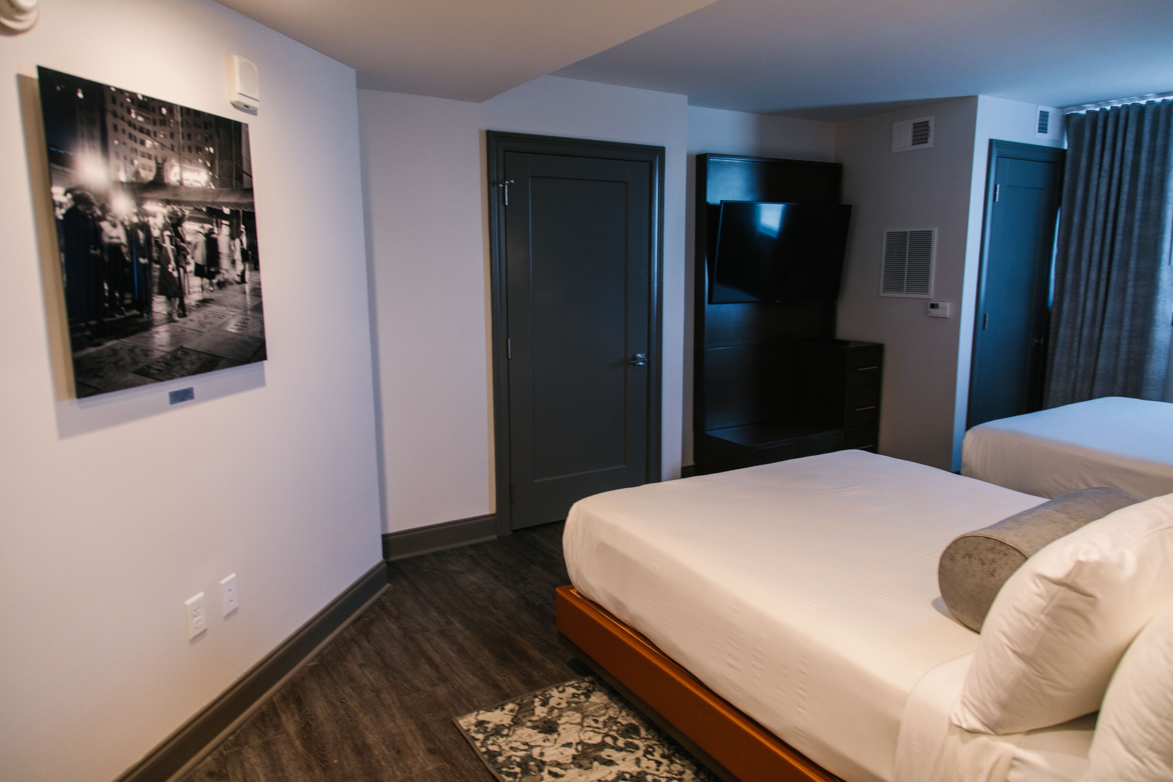 Une chambre d’hôtel avec un lit, une télévision, une porte et un tableau accroché au mur.