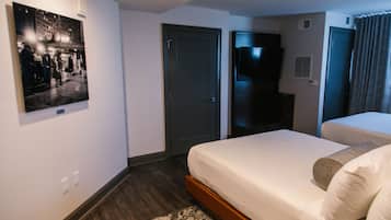 Une chambre d’hôtel avec un lit, une télévision, une porte et un tableau accroché au mur.