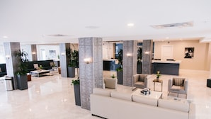 A spacious lobby with a reception desk, seating areas, and decorative plants. - The Hotel Legends (Biloxi)