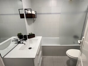 Un bagno moderno con un lavandino bianco, due erogatori di sapone neri, uno specchio e un water.