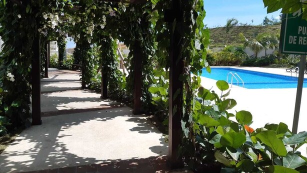 A covered walkway with a pool in the background. - Summer paradise, total relaxation on your vacation (Stgo)